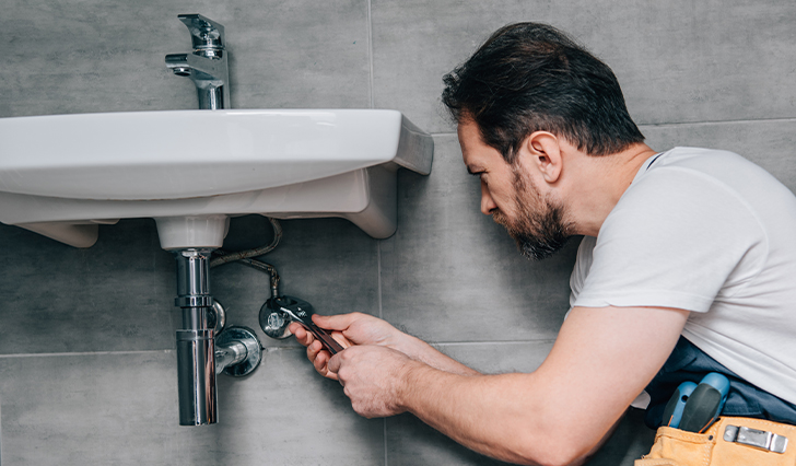 Plumber working below sink